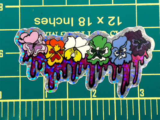 Colorful flower-shaped sticker with dripping effect on a green cutting mat.